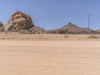 an empty, barren desert with rocks and sparse vegetation in the background under blue skies