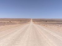 an empty desert road with a stop sign in the middle of it near the edge of the road