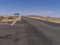 a road sign points left at a scenic intersection on a sunny day in the desert