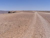 a road that is made from rocks in a desert area with mountains and a blue sky