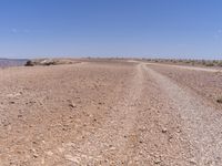 a road that is made from rocks in a desert area with mountains and a blue sky