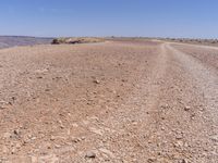 a road that is made from rocks in a desert area with mountains and a blue sky