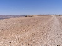 a road that is made from rocks in a desert area with mountains and a blue sky