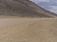 a small vehicle traveling across a barren road between some large rocks and boulders on one side