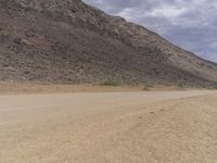 a small vehicle traveling across a barren road between some large rocks and boulders on one side