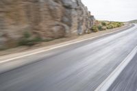 motorcycle rider turning right on empty highway surrounded by rocks and mountains in motion blurry