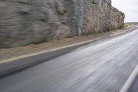 motorcycle rider turning right on empty highway surrounded by rocks and mountains in motion blurry