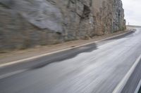 motorcycle rider turning right on empty highway surrounded by rocks and mountains in motion blurry