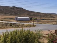 an empty road leading up a hill to a large white building and mountains in the distance