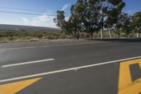 a stop sign painted with yellow paint is on the side of the road near a tree