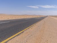 empty road near desert area with mountains in background, no people yet on it, in the distance are bushes and sparse clouds