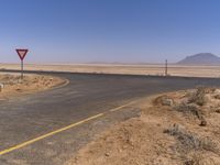 an empty street has a road sign for traffic along it, in the middle of a desert