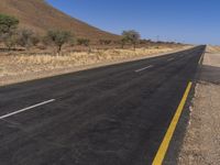 an empty road on the desert near a hill in the desert in the usa and a stop sign is in view