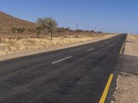 an empty road on the desert near a hill in the desert in the usa and a stop sign is in view