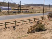 a view of an open road with telephone poles and some dirt grass and bushes around