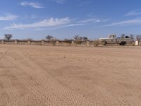 an old truck is parked along a road in the desert near a rail line lined with rails