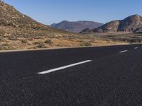 the empty road goes through two different mountains and has two lines painted in them to indicate where the lane will start