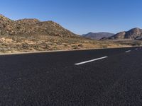 the empty road goes through two different mountains and has two lines painted in them to indicate where the lane will start