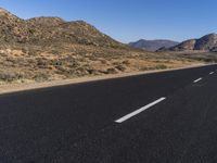 the empty road goes through two different mountains and has two lines painted in them to indicate where the lane will start