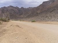 dirt road in desert with mountains behind it, and an orange stop sign that says no traffic