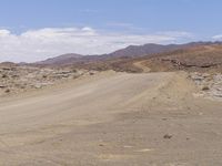 a person riding a motorcycle on a dusty road in the middle of nowhere in the desert