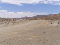 a person riding a motorcycle on a dusty road in the middle of nowhere in the desert