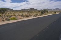 a long empty road in a desert landscape is seen from the passenger seat of a vehicle