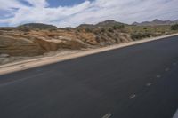 a long empty road in a desert landscape is seen from the passenger seat of a vehicle