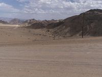 two motorcyclists riding down a dirt road in the middle of nowhere in the desert