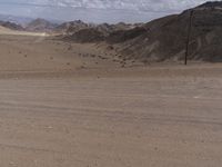 two motorcyclists riding down a dirt road in the middle of nowhere in the desert