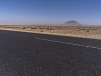 an open empty highway with an object in the distance in the desert of a state