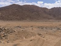 an open desert landscape with some rocks and dirt in it's foreground and hills on the background