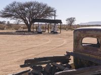 an old, rusty truck sitting in the middle of a dry area with a few signs around it