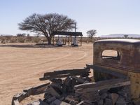 an old, rusty truck sitting in the middle of a dry area with a few signs around it