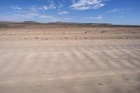 a desert area with some very sparse, dry grass and sparse sand on it's sides