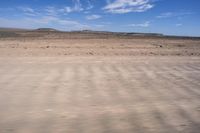 a desert area with some very sparse, dry grass and sparse sand on it's sides