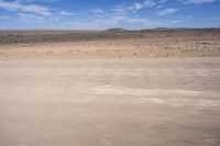 a desert area with some very sparse, dry grass and sparse sand on it's sides