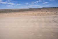 a desert area with some very sparse, dry grass and sparse sand on it's sides