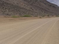 a small vehicle traveling across a barren road between some large rocks and boulders on one side