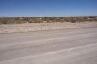 the view from a vehicle window on an empty street, looking out over dry scrubland and bare brush