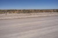 the view from a vehicle window on an empty street, looking out over dry scrubland and bare brush