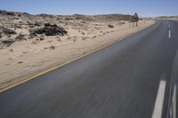 a red sign with white lines is on a desert road in the afternoon sun and blue sky