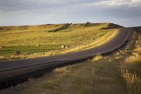 a highway with a few sheep graze on a grassy hill side, along the length
