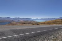 a motorcycle is going down an empty country road with mountain scenery in the background on a clear day