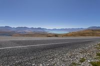 a motorcycle is going down an empty country road with mountain scenery in the background on a clear day