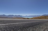 a motorcycle is going down an empty country road with mountain scenery in the background on a clear day