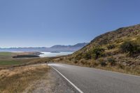 a large mountain road in the country side with mountains and the ocean on both sides