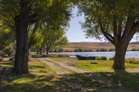 two boats parked on a field near a river and trees in front of it in the sunlight