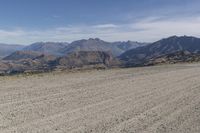 a desert area with rocks and a bike in the middle with mountains in the background