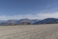 a desert area with rocks and a bike in the middle with mountains in the background